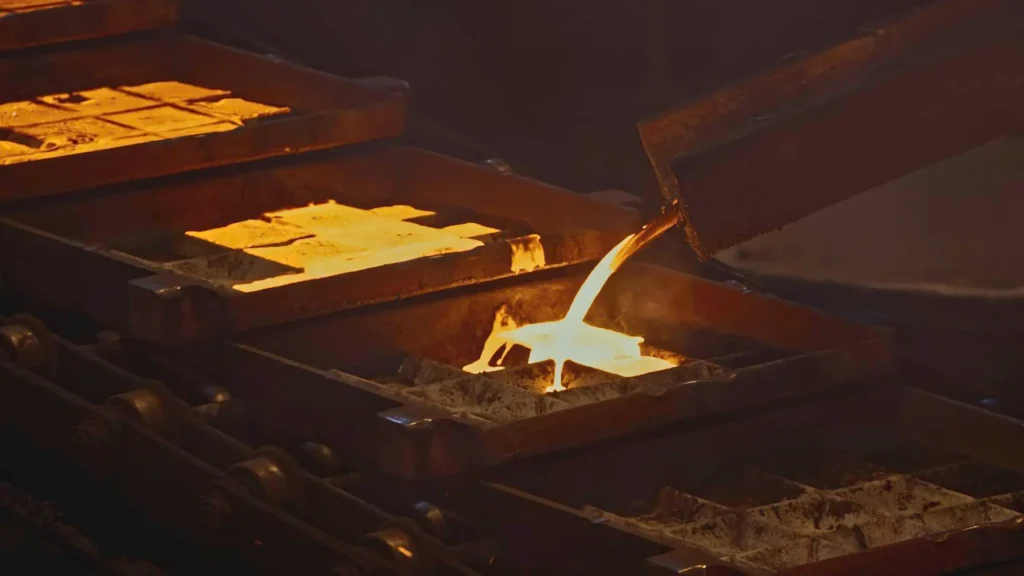 Molten metal being poured into molds, capturing the casting process in an industrial setting.