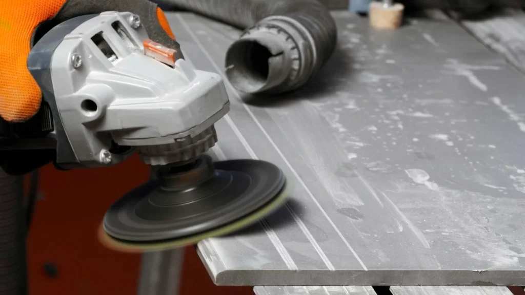 A worker using a grinding tool to polish and smooth a metal surface in preparation for further processing.