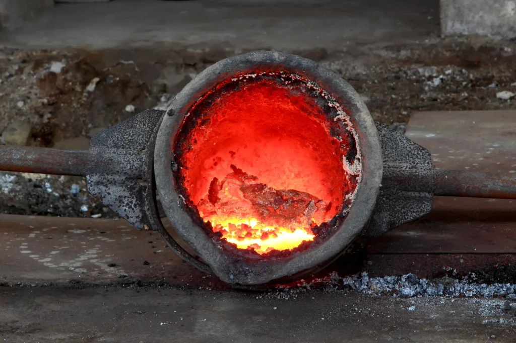 Close-up of a glowing crucible containing molten metal, highlighting the intense heat and industrial process.