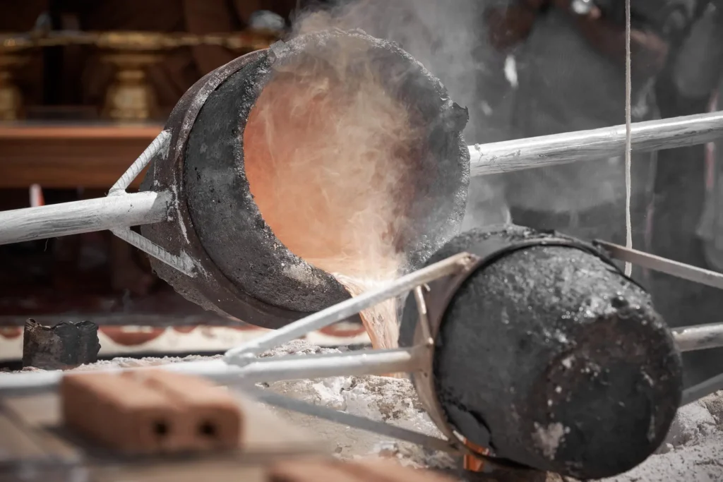 Molten metal pouring from a crucible into a mold setup, emphasizing the preparation for metal casting.