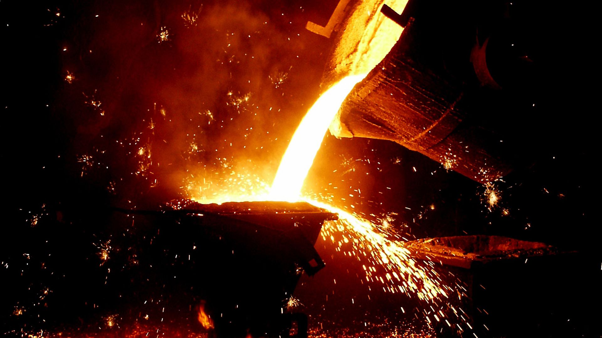 A foundry scene showing molten metal being poured from a crucible into a casting mold, with glowing sparks and intense heat.